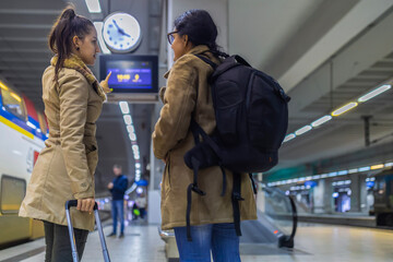 Women travelers checking departure information at train station