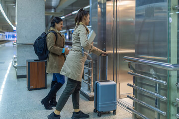 Woman with luggage calling elevator at subway station © Jelena