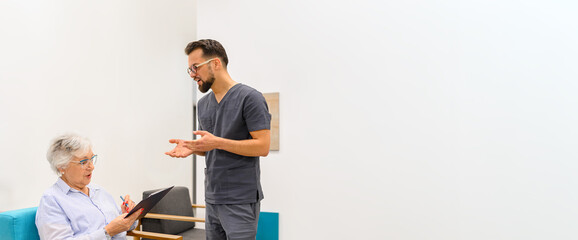 Male ophthalmologist explaining medical condition to senior patient reading medical records in hospital waiting room
