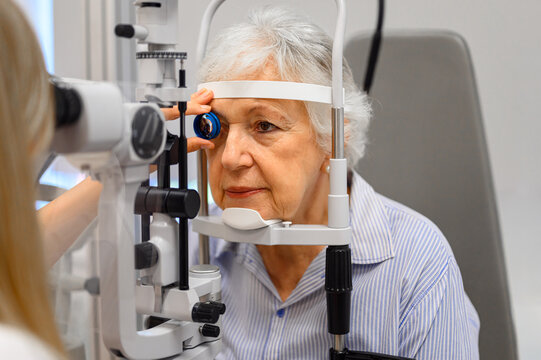 Cropped view of female ophthalmologist hand holding slit lamp for senior woman vision eye test at clinic