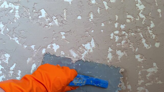Plasterer applying decorative venetian stucco on wall