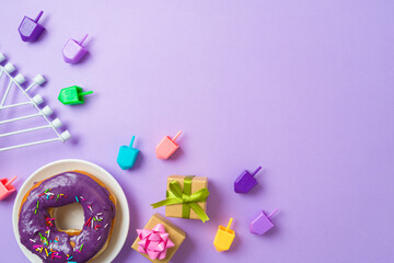 Jewish holiday Hanukkah concept with donuts, menorah, spinning tops and gift box on purple...