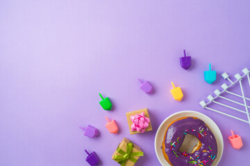 Jewish holiday Hanukkah concept with donuts, menorah, spinning tops and gift box on purple background. Top view, flat lay