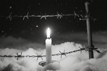 Solemn remembrance concept for Holocaust victims. Candle and wire symbolizing history and memory.