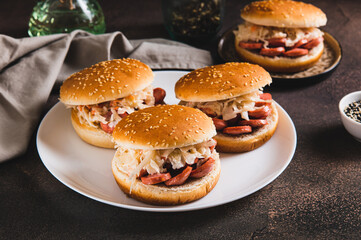 Burgers with grilled sausage and coleslaw on a plate on the table