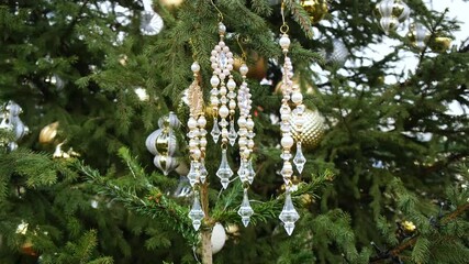 Luxurious crystal icicle garlands swinging slightly on tall public Christmas tree in city park create magical holiday scene for tourism promotion, event teasers, and seasonal branding videos