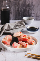 Crab sticks in rice paper with nori fried in oil on a plate on the table vertical view