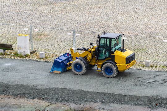Ein abgestellter Radlader am Bauzaun 
