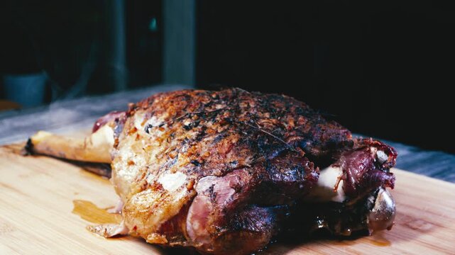 Smoking whole lamb leg on a wooden board, covered in aromatic seasoning. Perfectly cooked, ready to carve and serve. Ideal for festive meals and special occasions.