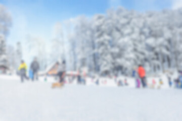 Blurred winter sledding hill with families playing
