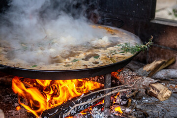 Traditional Valencian paella cooking process: adding a sprig of rosemary for aroma –...
