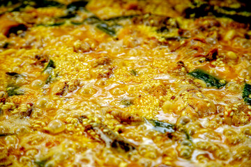 Traditional Valencian paella cooking process: rice cooking stage with broth reduction – Mediterranean cuisine in Spain.
