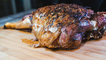 Whole roasted lamb leg with herb rub, golden brown crust, and aromatic seasoning on a wooden board. Juicy, tender, and ready to carve for a feast.