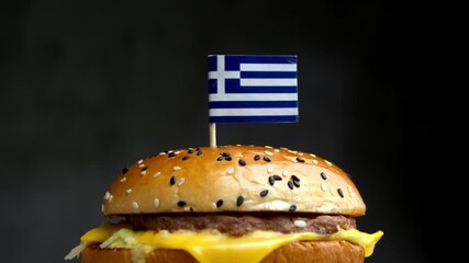 Close up burger with Greek flag, frame connects fast food with Greek meat, cheese and agricultural production. - Powered by Adobe
