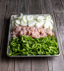 Sheet pan chicken fajitas with sliced onions, green bell peppers, and seasoned chicken arranged on a baking tray. Fresh, simple, and perfect for meal prep or easy dinner recipes.