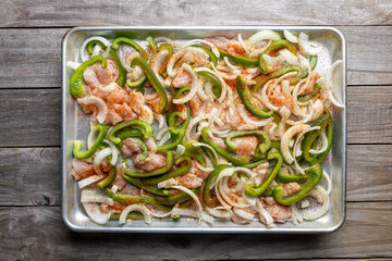 Sheet pan chicken fajitas with sliced onions, green bell peppers, and seasoned chicken arranged on a baking tray. Fresh, simple, and perfect for meal prep or easy dinner recipes.