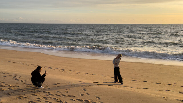 Tourist woman with camera take travel picture on beach at sunset. - Powered by Adobe