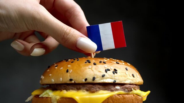 Close up burger with French flag, scene links gourmet fast food with French beef, cheese and bakery traditions.