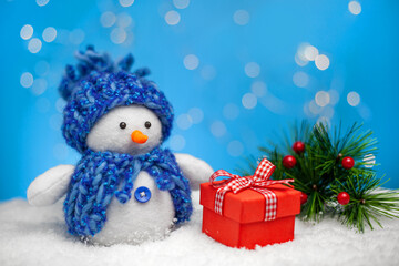 A Christmas or New Year's card. A funny snowman with a gift on a background of snow, winter and fir branches. handmade work.