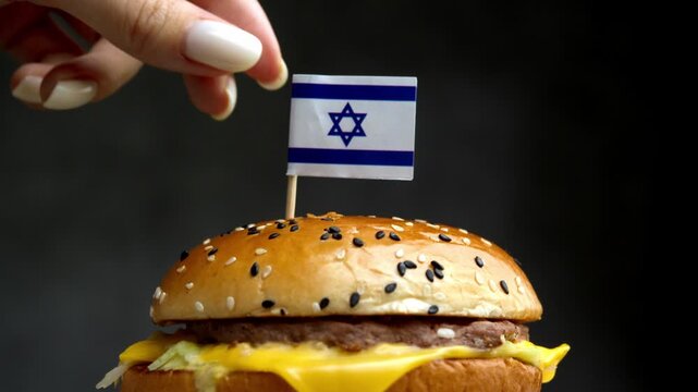 Close up burger with Israeli flag on toothpick, composition highlights local Israeli kosher meat and dairy production for fast food.
