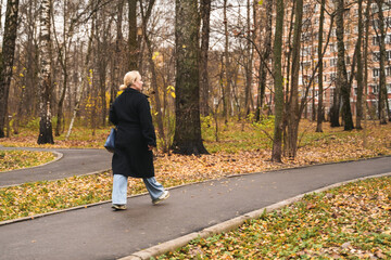 Walking woman on city park path. Outdoor exercise supports fitness, cardio, stress relief, mental health. Active lifestyle for adult leisure, long walk, daily routine, weekend recreation, nature.