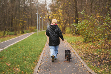 Walking woman with dachshund on park path. Sitting owner hugs small dog on bench. Outdoor pet care, city leisure, daily walk, companionship, stress relief, mental health, lifestyle, weekend activity.