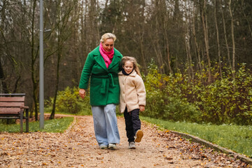 Walking mother with daughter on park path. Holding hands shows parenting, care, trust, safety. Outdoor family activity supports bonding, happiness, healthy lifestyle, weekend leisure, forest trail.