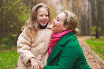 Cuddling mother with daughter in park. Smiling family portrait shows love, affection, support....