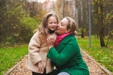 Obraz premium Cuddling mother with daughter in park. Smiling family portrait shows love, affection, support. Close bonding supports childhood happiness, motherhood care, trust, safe relationship, outdoor lifestyle.