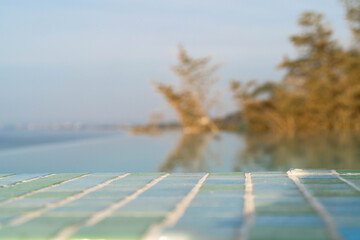 Relaxing by the tranquil sea, a luxurious spa setting features colorful mosaic tiles. The serene blue water reflects the clear sky and distant trees, evoking a sense of peace and serenity.