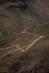 Top view of a winding dirt track road through rugged volcanic mountain terrain in Gran Canaria