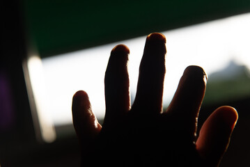 Hand Outstretched Against Illuminated Window