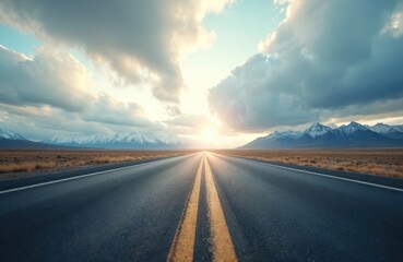 Empty asphalt road leads to snow-capped mountains under dramatic sky with bright sun. Dry grass covers vast plain. Journey ahead towards horizon.
