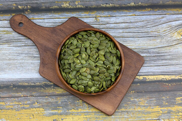 Pumpkin seeds in a wooden bowl on a wooden  background