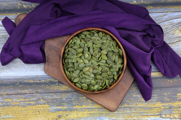 Pumpkin seeds in a wooden bowl on a wooden background