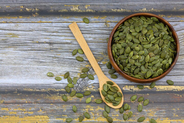 Pumpkin seeds in a wooden bowl on a wooden background