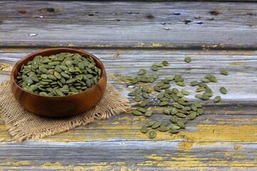 Pumpkin seeds in a wooden bowl on a wooden background