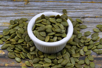 Pumpkin seeds in a wooden bowl on a wooden background