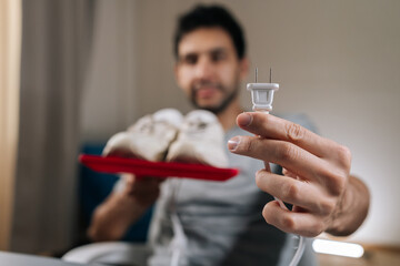 Focus on foreground of blurred male holding electric plug for shoe dryer, preparing to clean and...