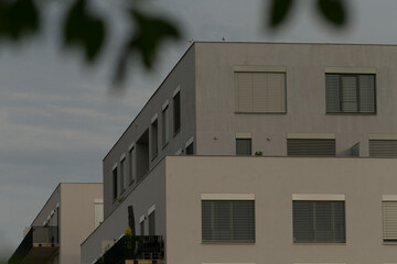 clean modern apartment block under overcast sky, simple cubic volumes and shuttered windows, calm...