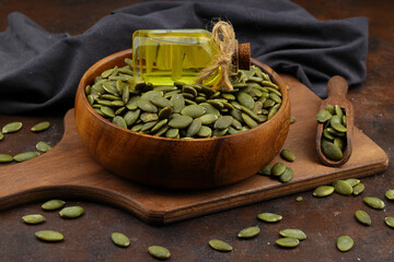 Pumpkin seeds in a wooden bowl on a wooden background