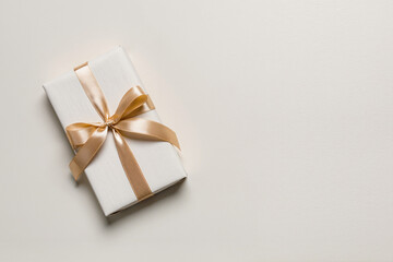 White gift box with golden ribbon and bow creating an elegant present for celebration, anniversary, holiday, or birthday