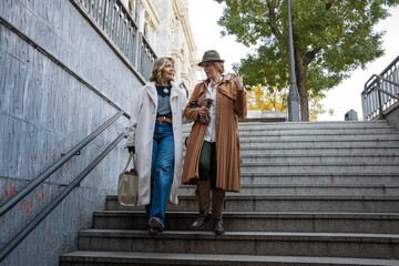 Two friends enjoy a lively conversation while walking down the staircase in a vibrant urban setting