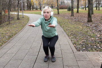 Fototapeta premium A woman with short blonde hair exercises in a park in nature. Sports and healthy lifestyle.