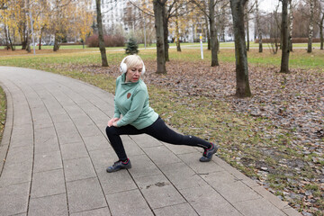 Fototapeta premium A woman with short blonde hair exercises in a park in nature. Sports and healthy lifestyle.