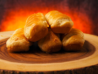Premium golden French brioche rolls on a wooden board with red hot burning style background. Fine and delicate dessert. Top quality pastry product.