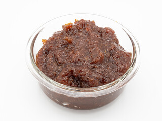 Rich brown indian lemon pickle in a glass bowl on a white background