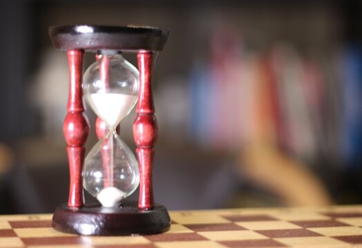 Hourglass as symbol of passing time and chess board photo