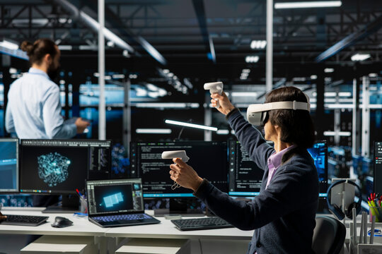 Data center programmer wearing VR goggles managing AI training datasets. IT worker using virtual reality tech, overseeing neural networks in server room supporting scalable equipment for AI apps - Powered by Adobe