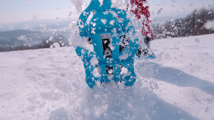 CLOSE UP, LOW ANGLE VIEW: Blue snowshoes pounded the fresh snow, creating an energetic blast of white powder in the bright sunlight and clear sky. Fun outdoor activity for cold and snowy winter days.